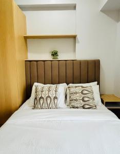 1 cama con cabecero marrón y almohadas en Modern-esque Room at Megaworld, en Iloilo City 11 fotos más