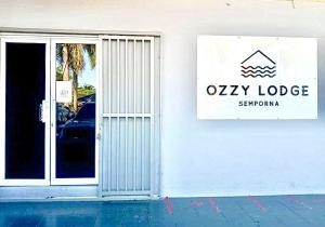 a white building with a sign on the side of it at Ozzy Lodge Semporna in Semporna
