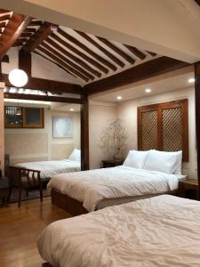 ein Schlafzimmer mit zwei Betten und einem Tisch darin in der Unterkunft Seoul Bukchon Homi Hanok in Seoul