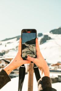 a woman holding up a cell phone in her hands at Hotel Glemmtalerhof in Saalbach Hinterglemm