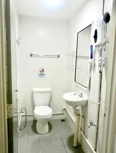 a white bathroom with a toilet and a sink at Ozzy Lodge Semporna in Semporna
