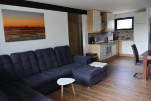 a living room with a couch and a kitchen at Nordseeferienhaus Emma Tossens in Butjadingen