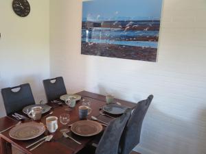 a dining room table with chairs and plates and a picture at Nordseeferienhaus Emma Tossens in Butjadingen