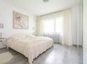 a white bedroom with a bed and a window at Ferienhaus Burgblick in Hürtgenwald