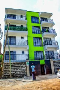 a man standing in front of a green and white building at Essence Urban Homes STUDIO in Kisumu +8 photos
