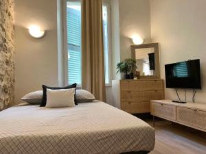 a bedroom with a bed with a television and a dresser at Studio dans le vieil Antibes in Antibes