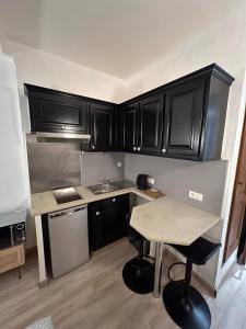 a small kitchen with black cabinets and a table at Studio dans le vieil Antibes in Antibes