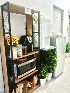 a microwave on a shelf in a kitchen with plants at Ozzy Lodge Semporna in Semporna