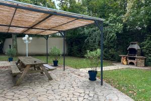 a picnic table and a grill in a backyard at Clos des chênes in La Houssaye-en-Brie