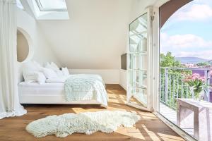 ein weißes Schlafzimmer mit einem Bett und einem großen Fenster in der Unterkunft Boutique Suites and Residences Heidelberg- Alte Zigarrenmanufaktur in Heidelberg + 21 Fotos