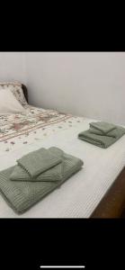 two green towels are sitting on a bed at Mimi's House 1 in Chios