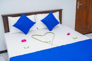 a bed with blue pillows and flowers on it at RKM Hotel Uppuveli in Trincomalee