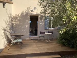 a wooden deck with chairs and a table on a house at St-Quentin la Poterie villa clôturée pour 4 pers avec jardin in Saint-Quentin-la-Poterie