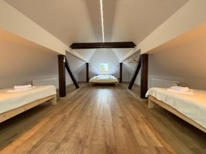 a room with two beds in a attic with wooden floors at Kuźnia-Grodno in Krzywa Wieś