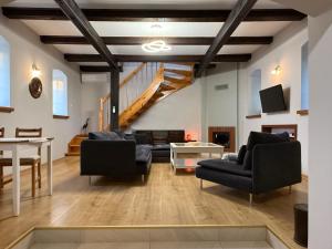 a living room with black furniture and a staircase at Kuźnia-Grodno in Krzywa Wieś