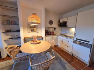 a kitchen with a wooden table and chairs in a kitchen at Feriendorf Rugana - Komfortplus 1-Raum Ferienwohnung mit Terrasse A59 in Dranske