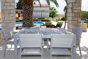 a white dining table and chairs on a patio at Apartments Diana - NEW heated pool in Bol +24 photos