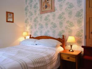 a bedroom with a bed and a wall with floral wallpaper at Gable Cottage in Keswick +2 photos