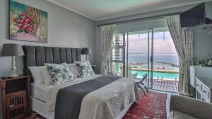 a bedroom with a bed and a view of the ocean at 3ColoursBlue Guest House in Mossel Bay