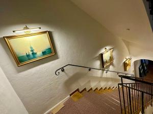 a staircase with a painting of a lighthouse on the wall at Hotel Bergen Zur Post by Rikas Hotels in Bergen +42 photos