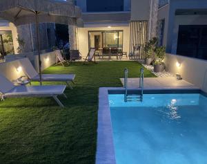 a backyard with a swimming pool at night at Trinity Pool Villas GOLD in Iraklitsa