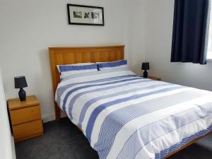 a bedroom with a bed with blue and white stripes at Little Dover Cottage in Ryde