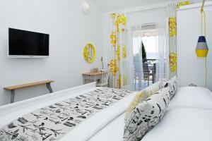 a white bedroom with a bed and a tv at Apartments Diana - NEW heated pool in Bol +41 photos