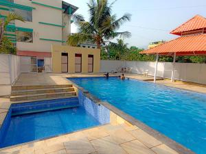 a large swimming pool with blue water in front of a building at Atithi farmhouse in Alibaug