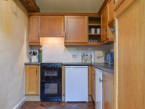 a kitchen with wooden cabinets and a black and white dishwasher at Swallows - Uk41742 in Mayfield