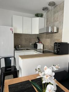 a kitchen with white cabinets and a table at Luxus Cluj Airport Apartments in Cluj-Napoca