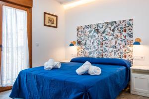 a bedroom with a blue bed with towels on it at Quercus in Navaluenga