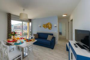 a living room with a blue couch and a table with food on it at Résidence Goélia Le Phare in Le Tréport