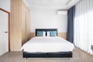 a bedroom with a large white bed with blue pillows at Naka Villa at Pratumnak in Pattaya South