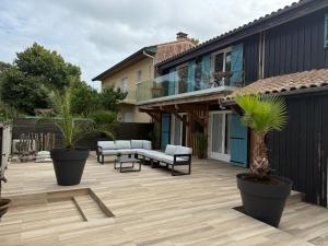 a patio with furniture and palm trees on a house at Villa JANE vue Bassin in Lège-Cap-Ferret