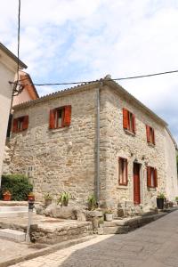 an old stone building with red shuttered windows at Rooms Poli Luce - Room Pepa in Gračišće