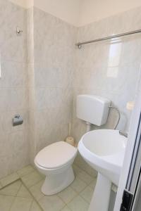 a white bathroom with a toilet and a sink at Hotel Ardian in Golem