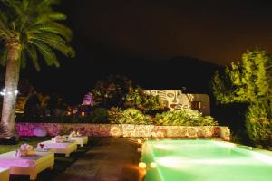Una piscina en un resort por la noche con mesas. en Chic 6 Bedroom Villa in Ibiza City, 1259, en Portinatx