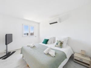 a white bedroom with a bed and a flat screen tv at Résidence Aigue Marine in Coti-Chiavari