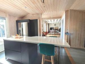 a kitchen with a large counter with two green chairs at Villa JANE vue Bassin in Lège-Cap-Ferret