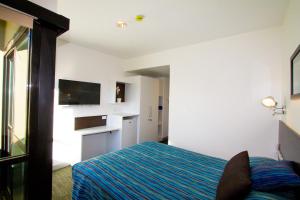 a bedroom with a bed and a flat screen tv at The Landing Port Hedland in Port Hedland