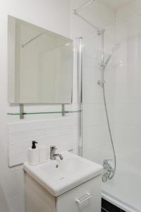 a white bathroom with a sink and a shower at La Madeleine -two bedroom apartment in La Madeleine