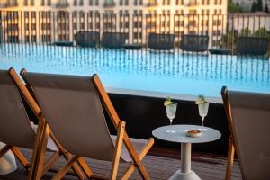 2 chaises et une table avec 2 verres à vin dans l'établissement Hotel Nucha-Fattal Colors, à Jérusalem