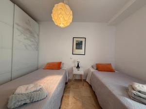 two beds in a white room with a lamp at 18 Torres Santa Cruz in Zaragoza