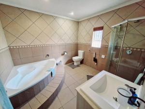 a bathroom with a tub and a toilet and a sink at Rockhound in Boksburg +7 photos