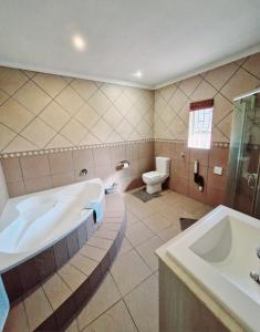 a bathroom with a tub and a toilet and a sink at Rockhound in Boksburg