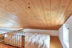 a bed in a room with a wooden ceiling at 300m plage - Petite maison avec jardin pour 3 in LʼÉpine