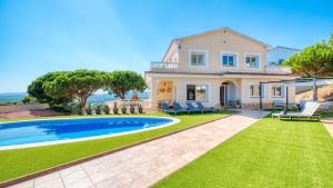 a villa with a swimming pool and a house at Costacabana - Villa Ibiza in Lloret de Mar
