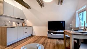 a kitchen with white cabinets and a flat screen tv at Willa Muszelka - Apartamenty in Świnoujście