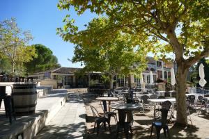 Un patio con mesas y sillas y un árbol. en Appartement clim & piscine sur Golf, en Pont-Royal