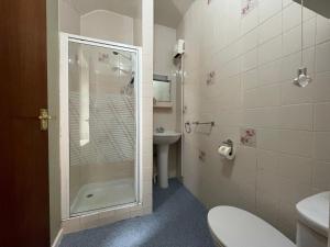 a bathroom with a shower and a toilet and a sink at Wedgwood Hotel, Seascape Room in Llandudno